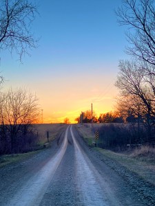 Long, gravel road at sunset.